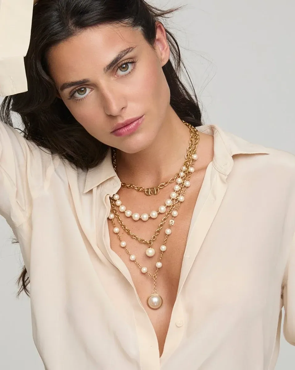 Gros plan du collier à quatre rangs de perles porté sur le cou d'un modèle, fond neutre clair.