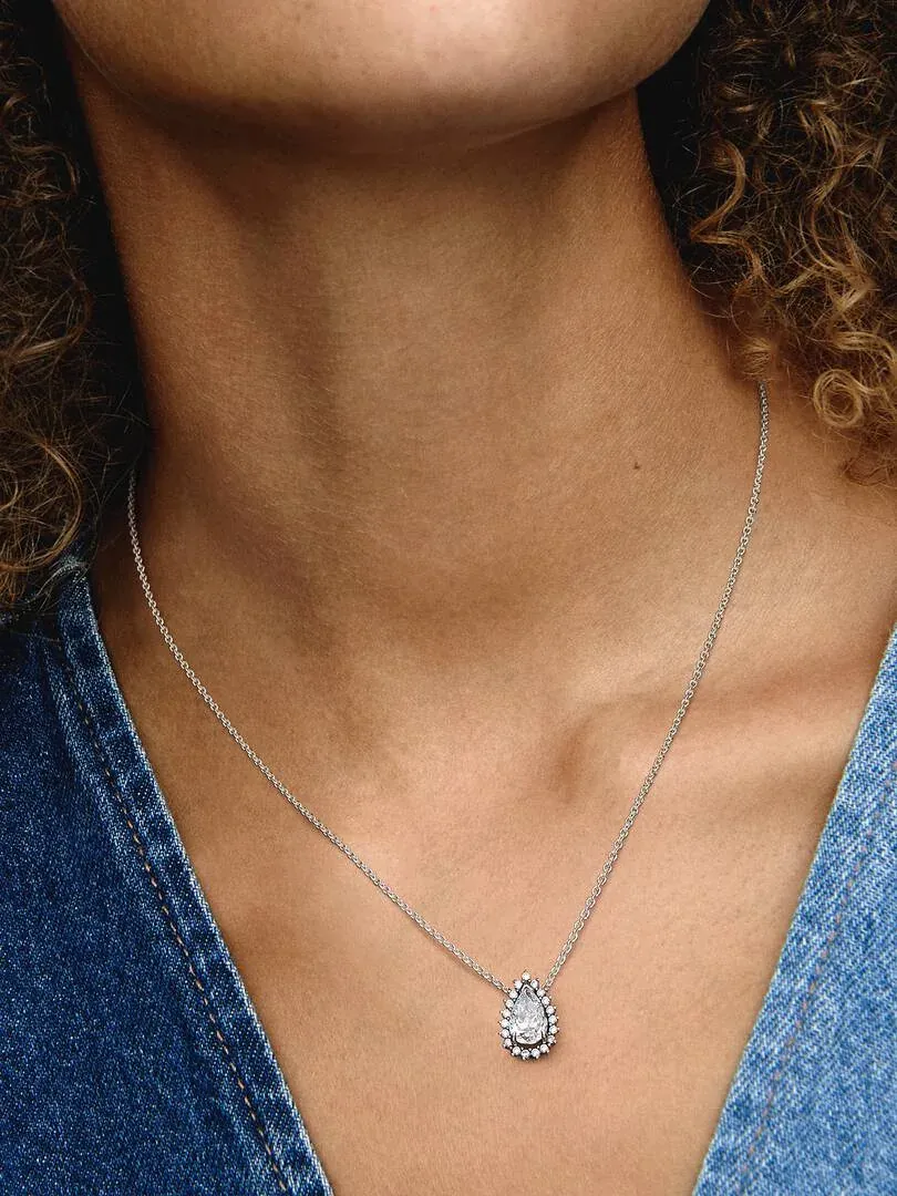 Gros plan du pendent en forme de poire sur le cou d'un modèle, portant un haut bleu, vue de face.