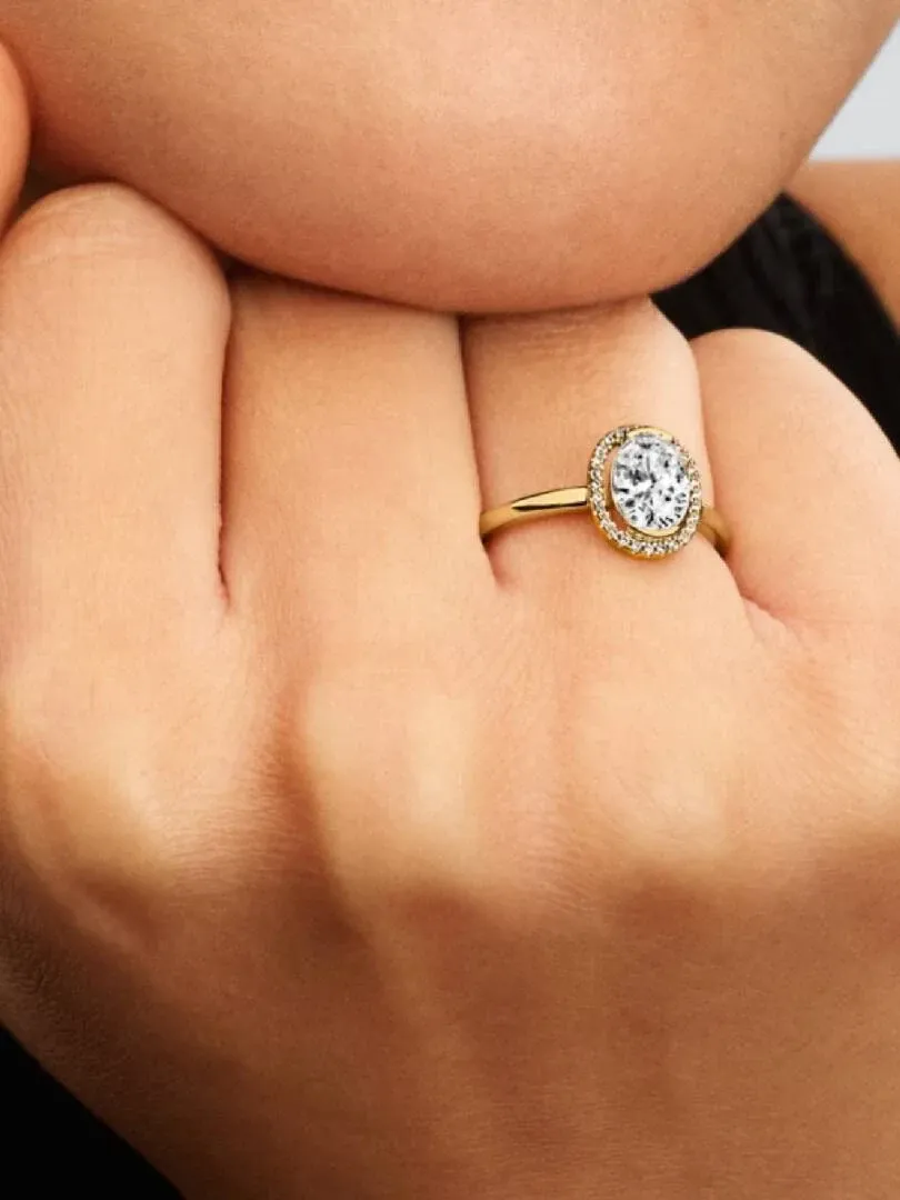 Primer plano del anillo con gema ovalada puesto en el dedo, toma lateral sobre fondo oscuro desenfocado.