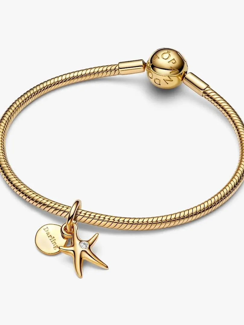 Bracelet chaîne dorée avec charm étoile de mer et médaillon gravé, vue de face sur fond blanc.