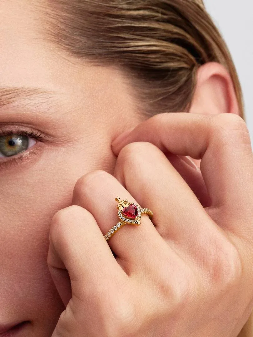 Primer plano del anillo con cristal rojo en forma de corazón puesto en el dedo, toma lateral sobre mano.