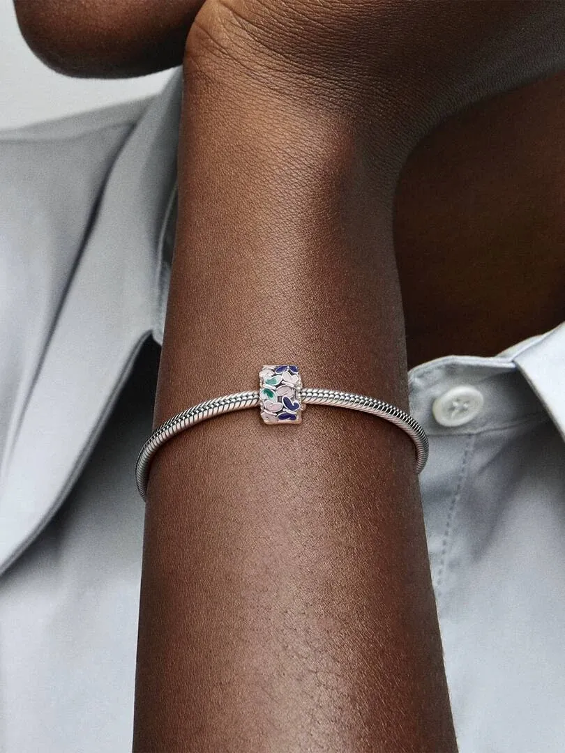 Close-up of a bracelet with enamel butterfly charm on a wrist, side view against a neutral background.