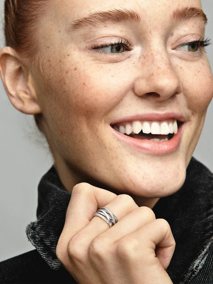 Close-up van een lachende vrouw met de ring om haar vinger, zijaanzicht tegen een neutrale achtergrond.