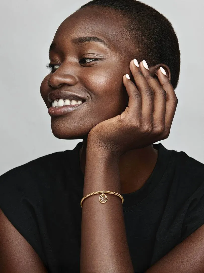 Close-up van een vrouw met de Sagittarius charm aan haar armband, zijaanzicht tegen een neutrale achtergrond.