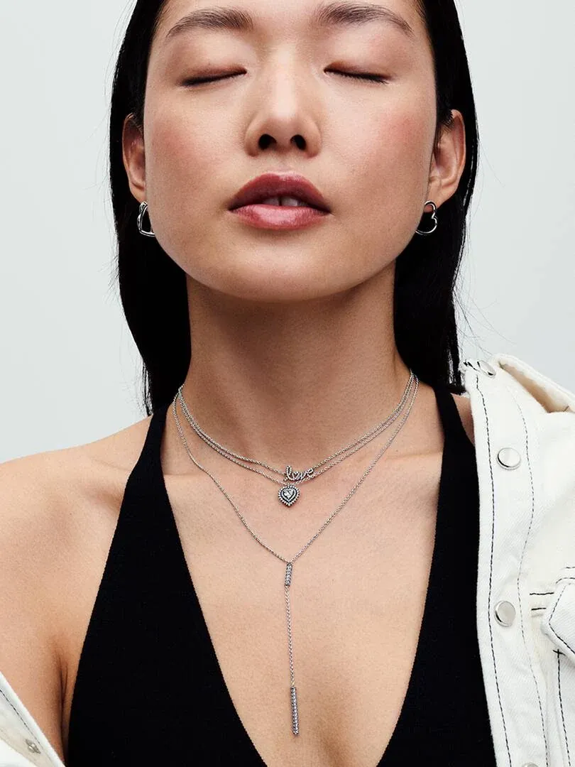 Gros plan du collier à deux rangs avec pendentif cœur sur le cou d'un mannequin, fond neutre.