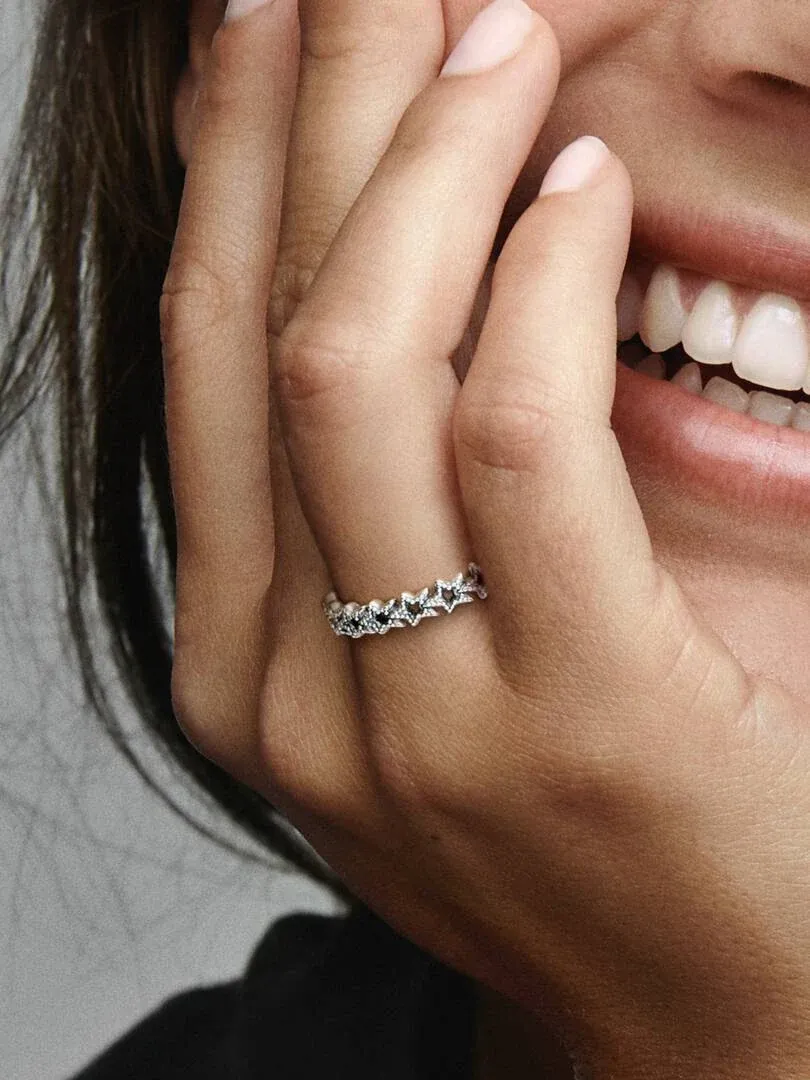 Nahaufnahme des Sternenrings am Ringfinger, Seitenansicht mit lächelndem Modell im Hintergrund.