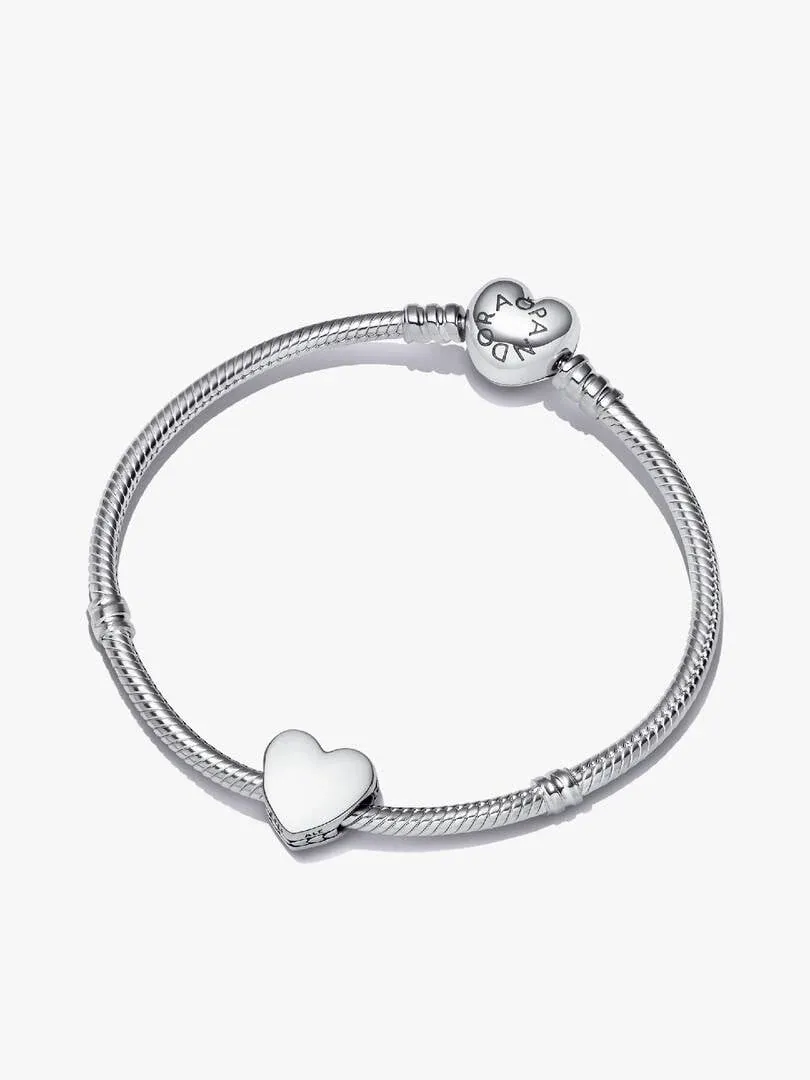 Pulsera de plata vista desde arriba en ángulo inclinado, sobre fondo blanco, mostrando el cierre y charm de corazón.