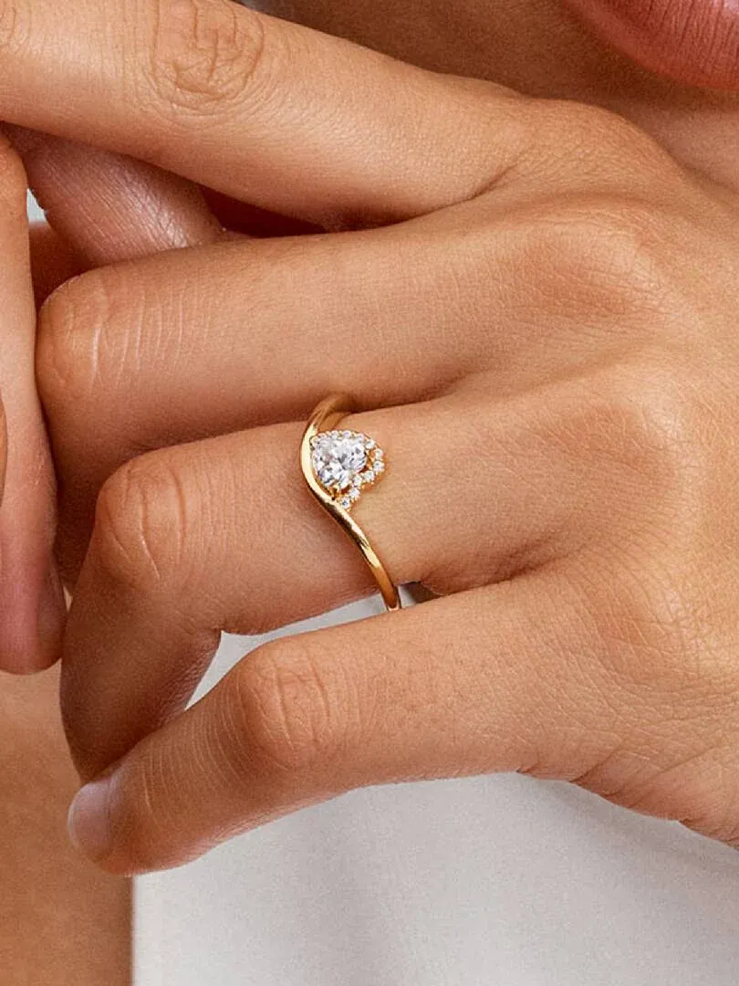 Primer plano del anillo con gema de corazón puesto en el dedo, toma lateral sobre piel.