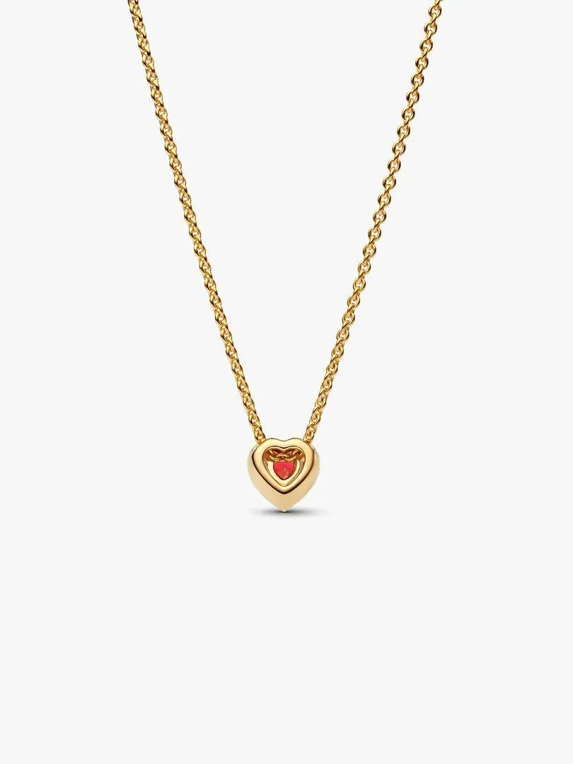 Collier avec pendentif cœur doré et pierre rouge, vue de face sur fond blanc.