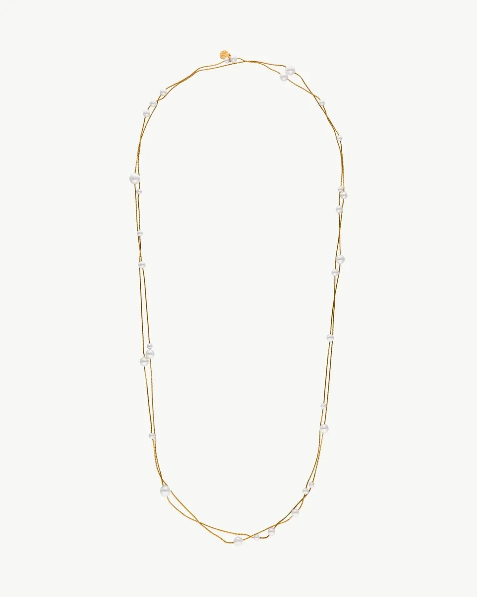 Long pearl and gold chain necklace arranged in a U-shape on a white background.