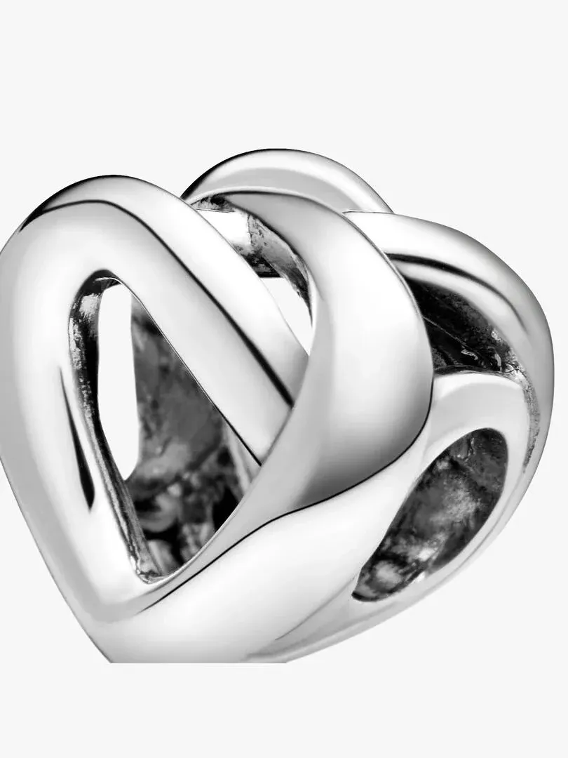 Close-up van de zilveren knoop charm, zijwaarts aanzicht met focus op reliëf en glans, witte achtergrond.