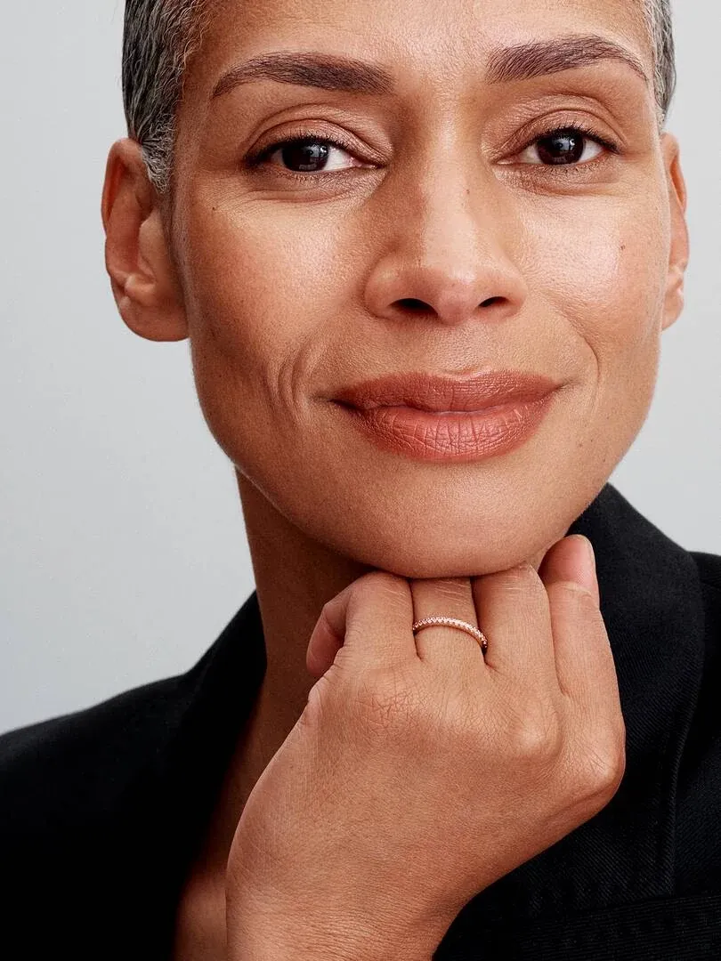 Primer plano de una mujer con el anillo en el dedo, toma frontal con fondo neutro claro.