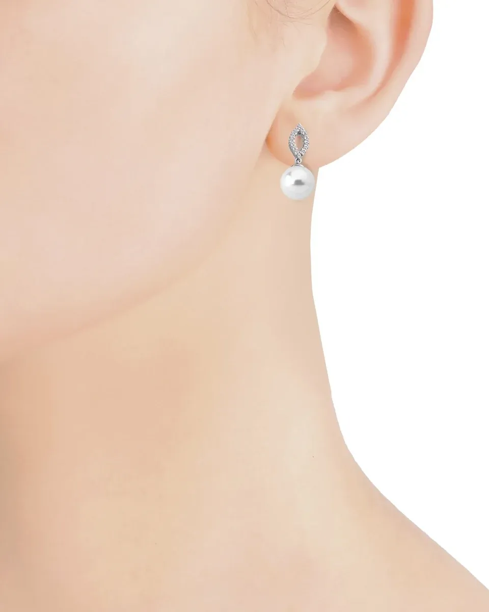 Gros plan latéral d'une boucle d'oreille en perle et zircons portée sur le lobe de l'oreille.
