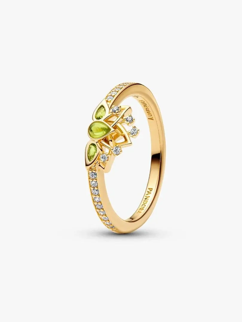 Anillo de tiara visto en ángulo lateral, fondo blanco, detalle de gemas verdes y brillantes sobre banda dorada.