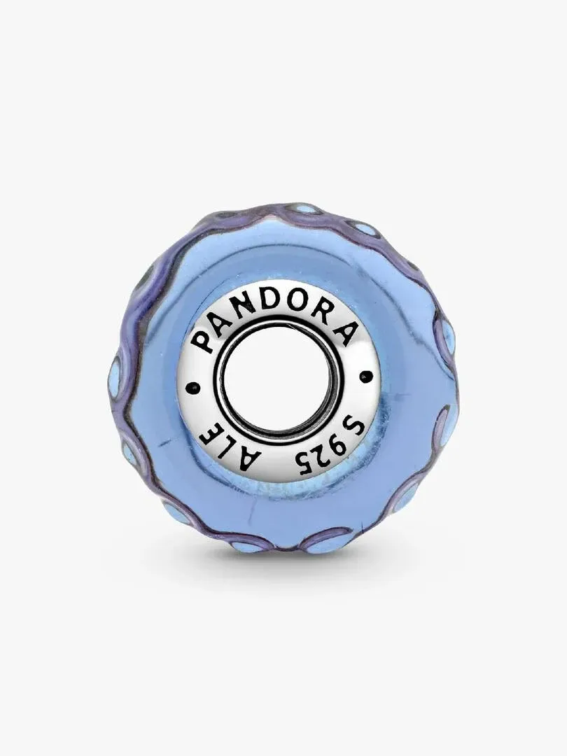 Gros plan du charm en verre bleu avec gravure de la marque sur le centre en argent, fond blanc.