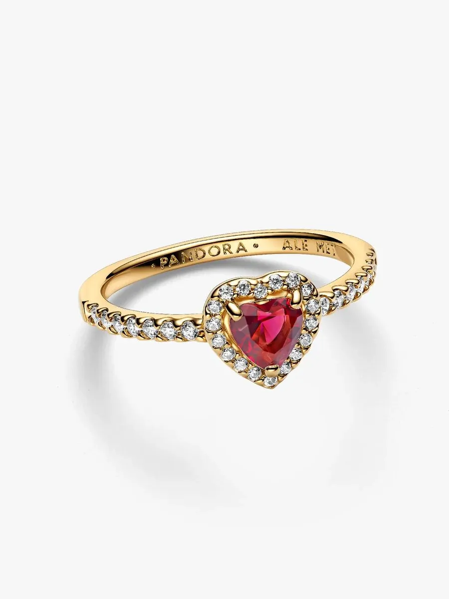 Anillo con corazón rojo visto en ángulo lateral, fondo blanco, detalle de la banda con pavé de circonitas.