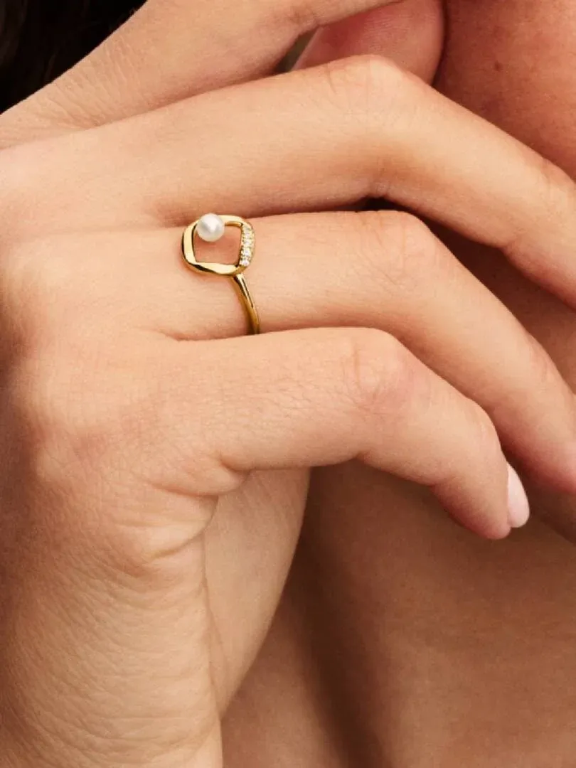 Primer plano del anillo con perla y circonitas puesto en el dedo, toma lateral sobre piel.