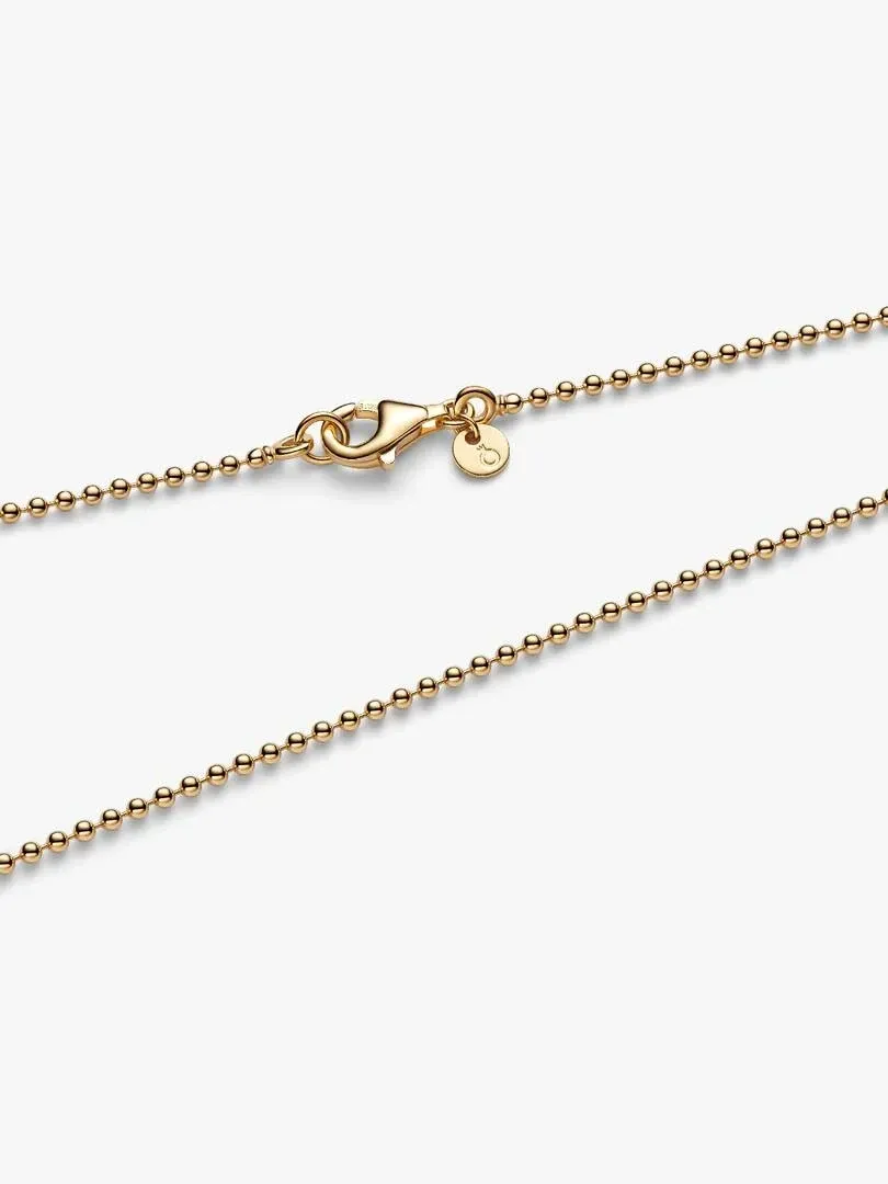 Close-up of the lobster clasp and gold bead chain on a white background.