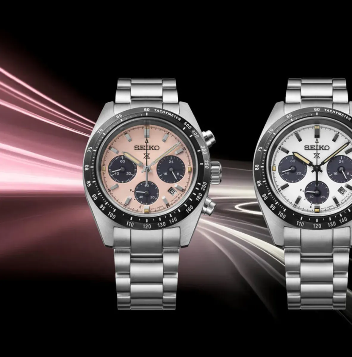Vista frontal de dos relojes con esferas en tonos salmón y blanco, fondo negro con efectos de luz sintéticos.