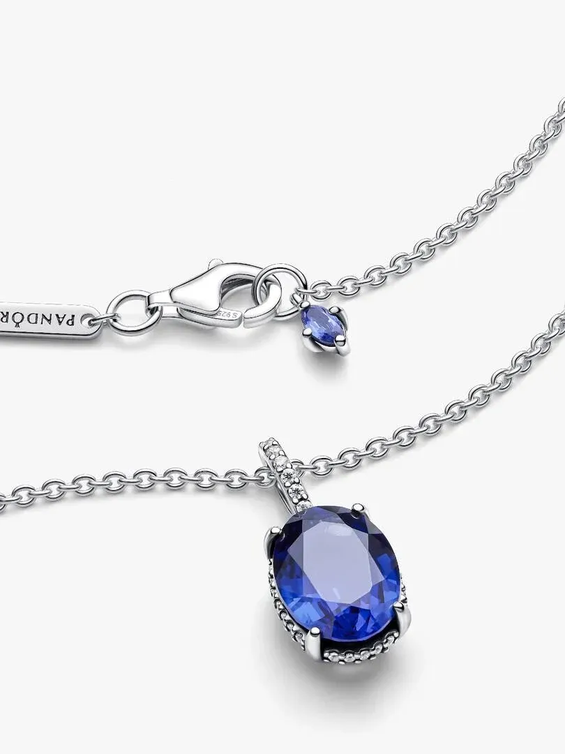 Primer plano del colgante ovalado azul y el cierre de plata sobre fondo blanco.