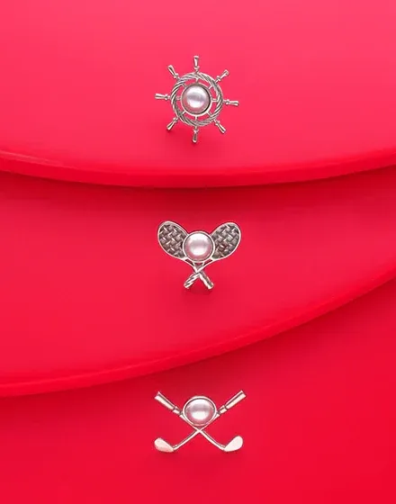 Trois épingles en acier avec perles disposées en diagonale sur des surfaces rouges courbes.