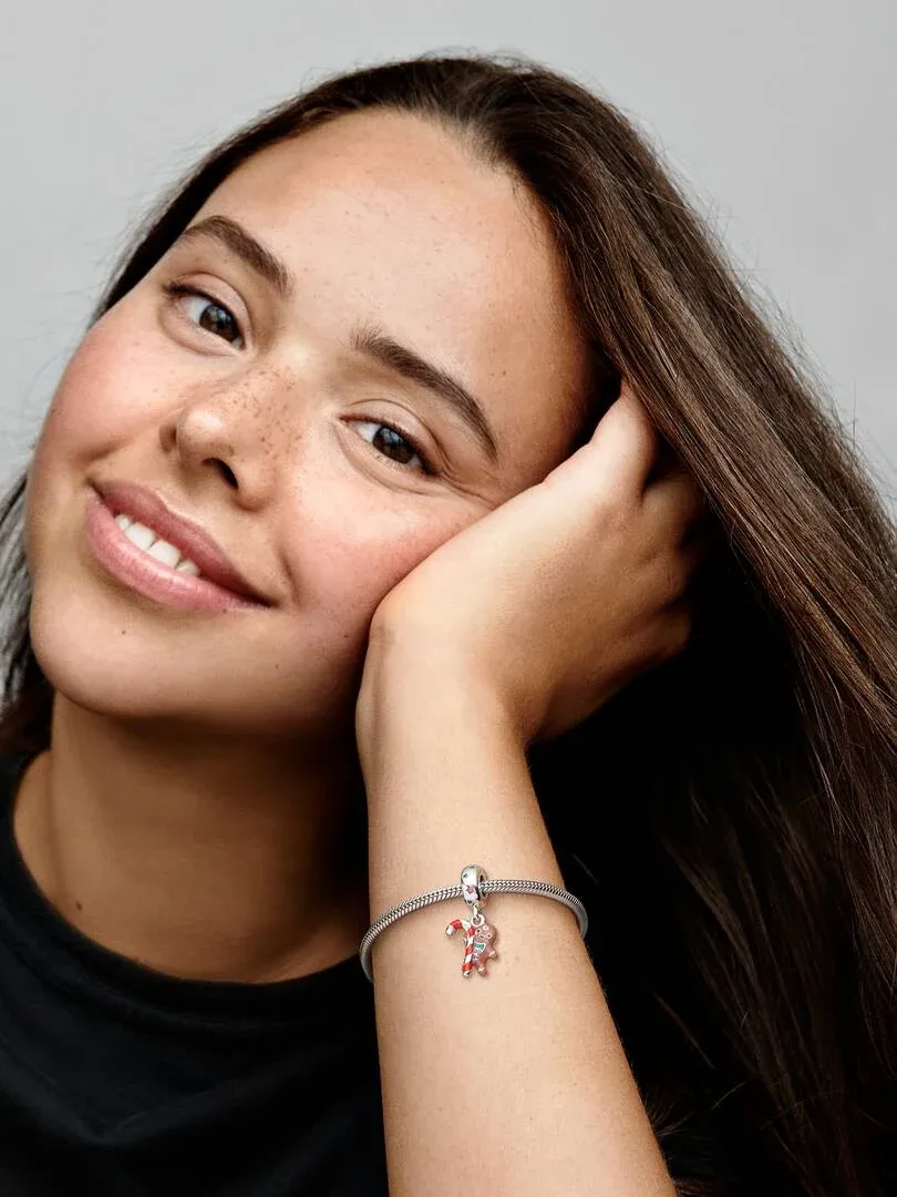 Close-up of the gingerbread charm on a wrist, model resting her head on her hand against a neutral background.