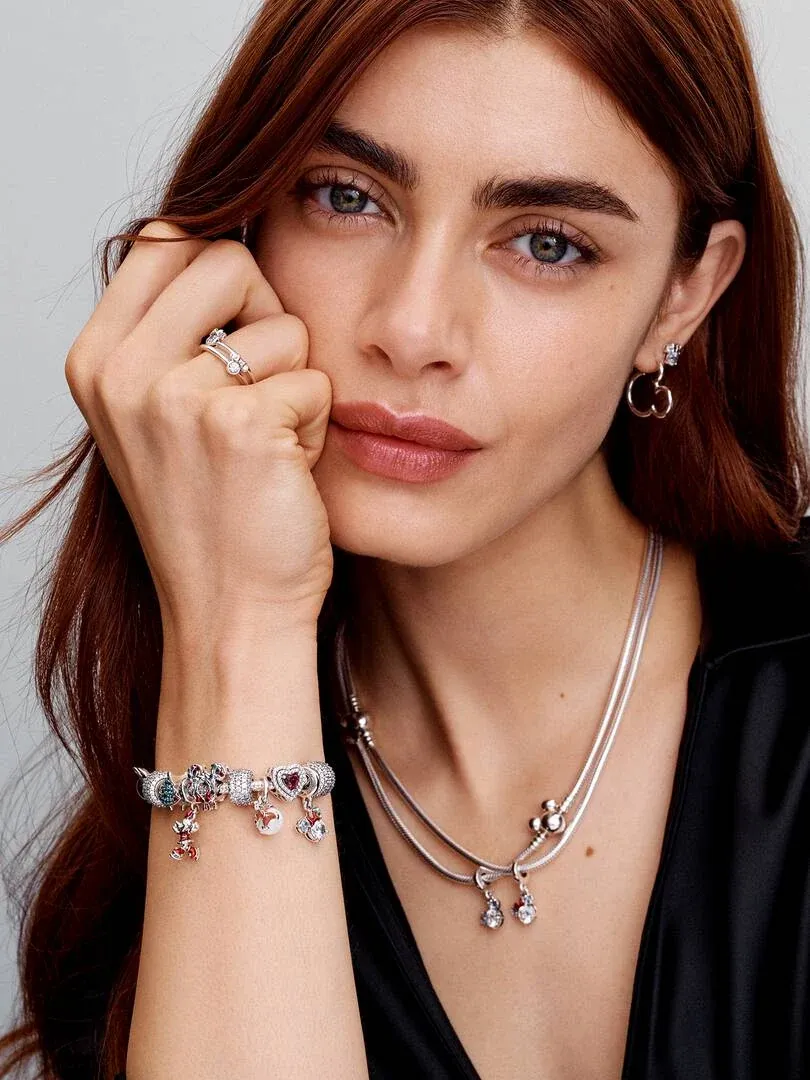 Modelo con collar de plata, pulsera con charms y pendientes de aro, toma frontal de plano medio.