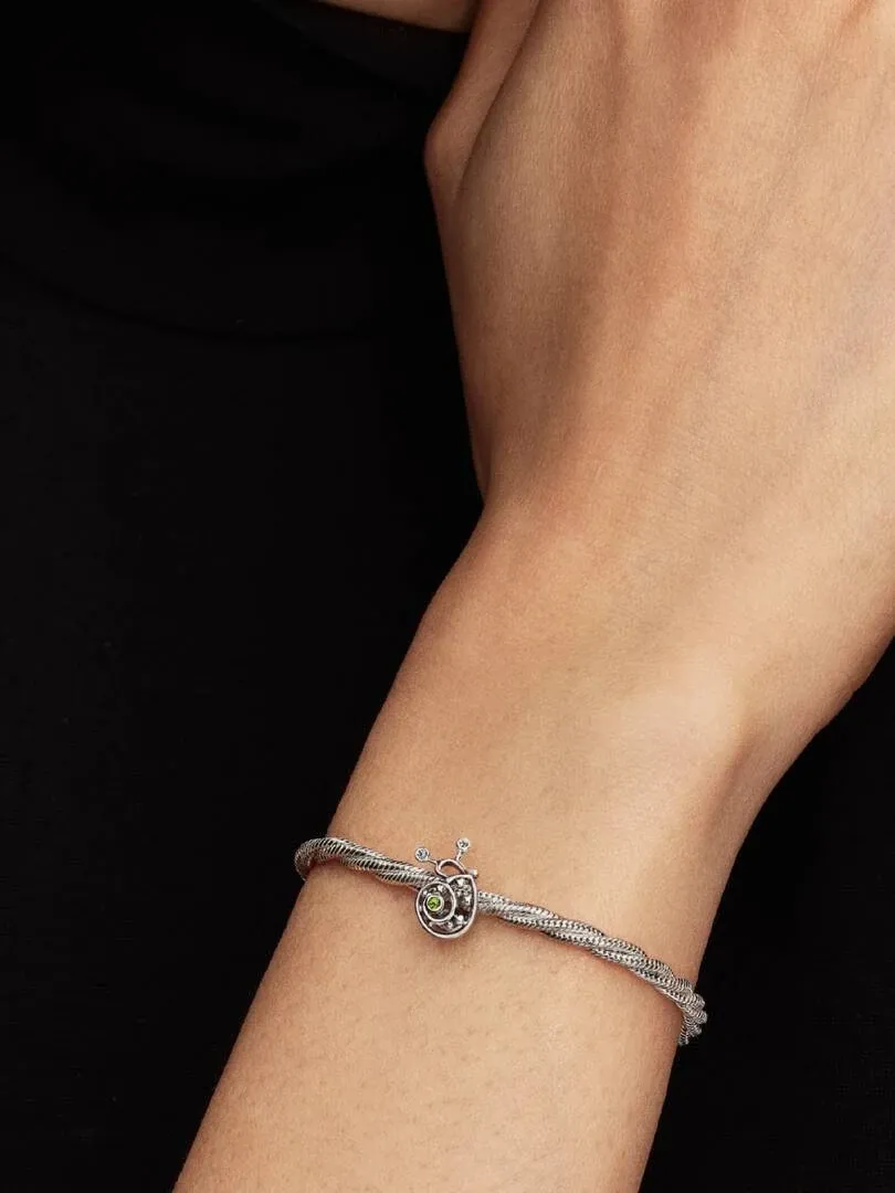 Charm de caracol con filigrana puesto en una pulsera de plata, toma lateral sobre la muñeca.