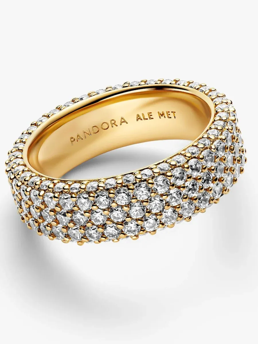 Anillo de tres filas visto en ángulo picado, fondo blanco, detalle del grabado interno y pavé de circonitas.