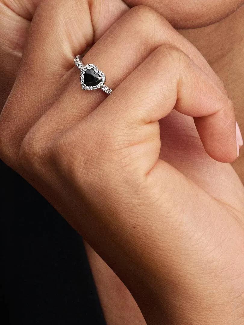 Close-up van de ring met zwarte hartvormige steen gedragen aan een vinger, zijaanzicht op de huid.