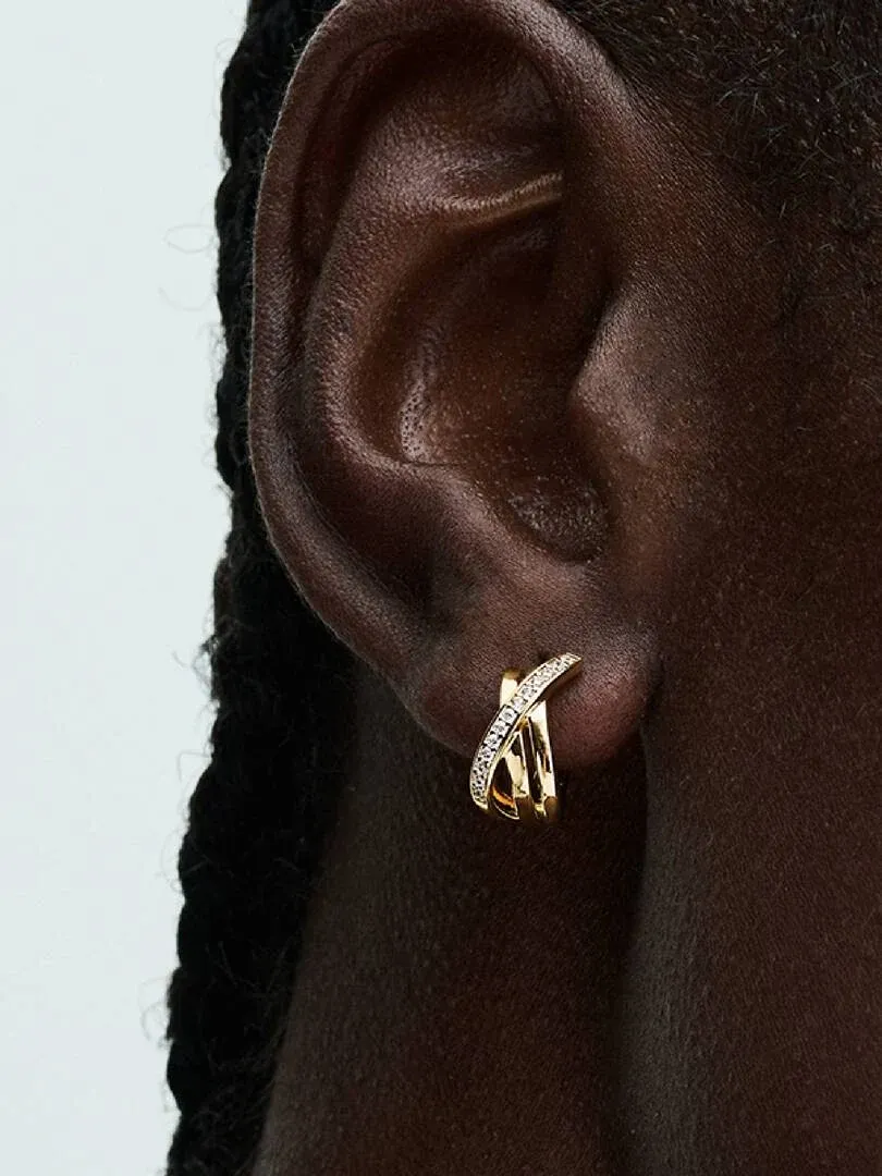 Side close-up of a gold hoop earring with cubic zirconia pavé worn on an earlobe.