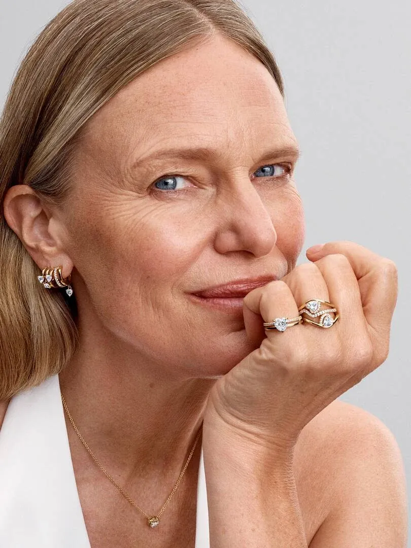 Primer plano de modelo con anillo de doble alianza y collar, toma lateral apoyada en la mano.