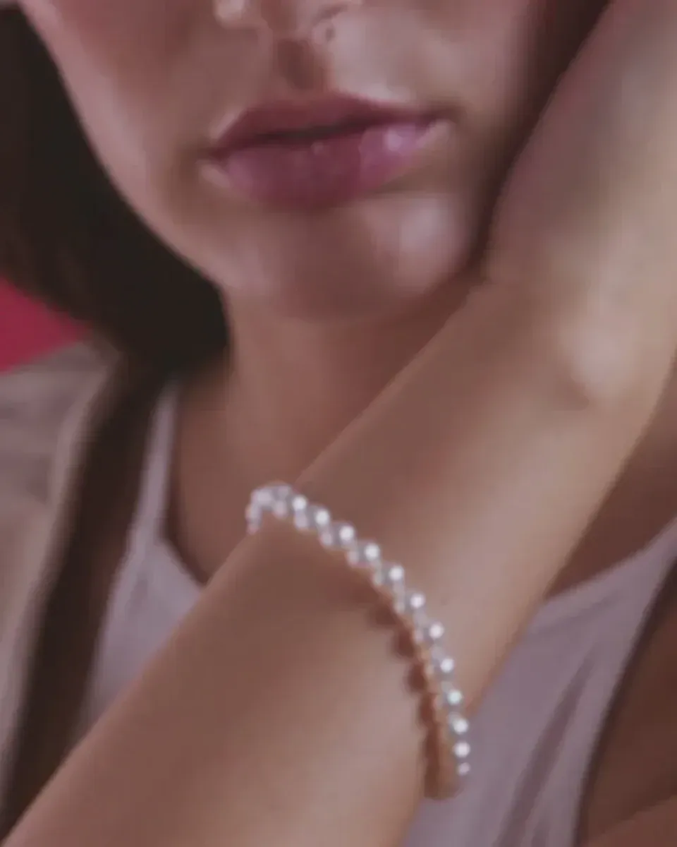 Gros plan d'un bracelet en perles porté au poignet, arrière-plan flou avec le visage du mannequin.