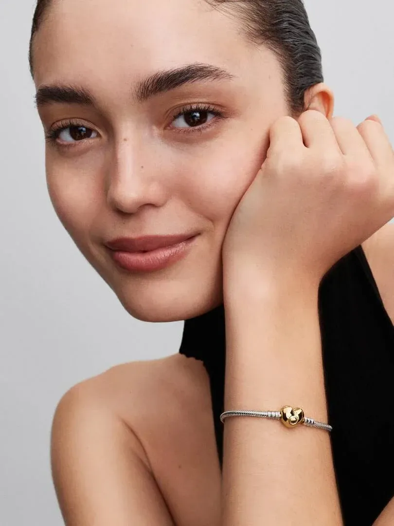 Primer plano de la pulsera en la muñeca, toma lateral con modelo sobre fondo neutro.