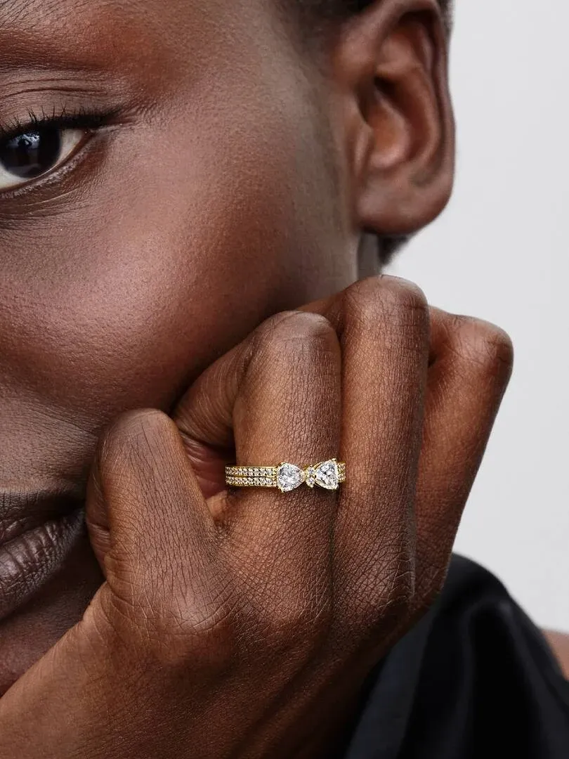 Primer plano del anillo de lazo con circonitas sobre el dedo de una modelo, toma lateral con fondo neutro.