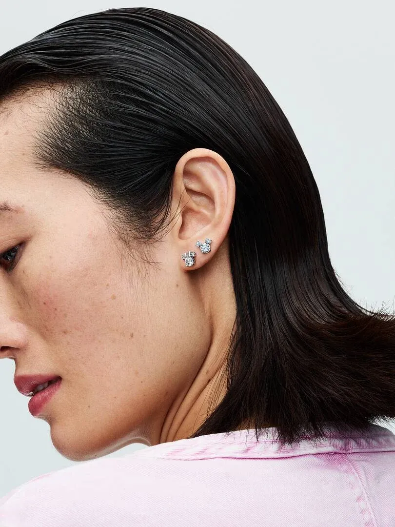 Nahaufnahme im Profil einer Modellin, die die Mickey und Minnie Ohrstecker trägt, neutraler Hintergrund.