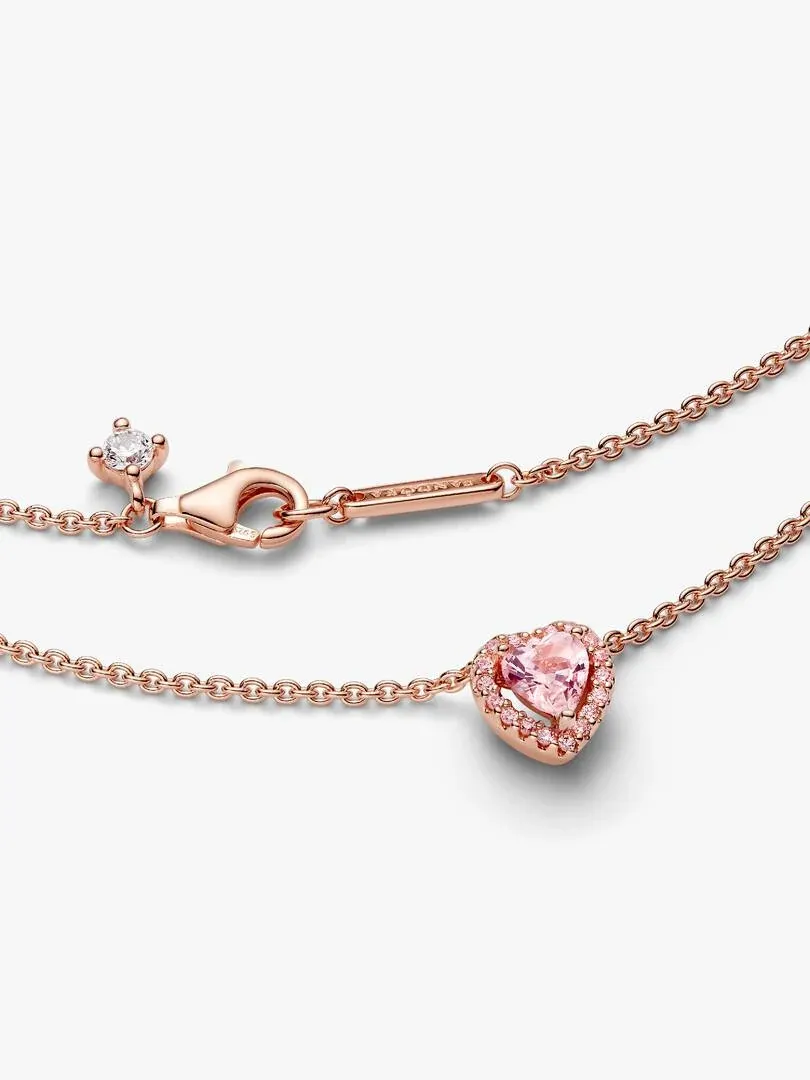 Gros plan du pendentif cœur rose et du fermoir de la chaîne sur fond blanc.