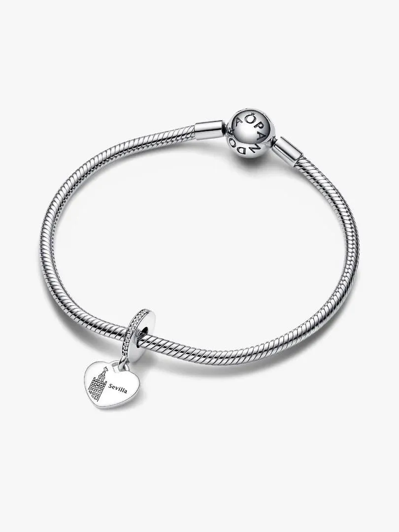 Pulsera de plata con charm de corazón grabado, vista superior diagonal sobre fondo blanco.