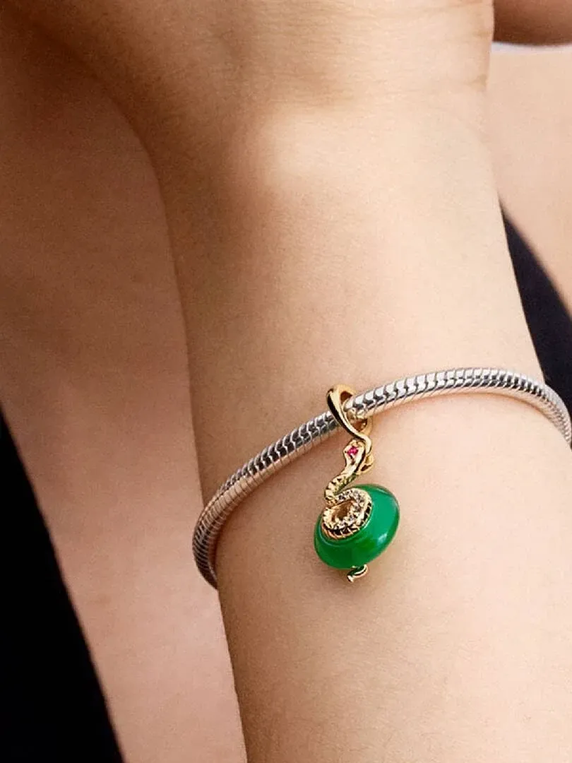 Close-up van de slang charm aan een schakelarmband, gedragen om de pols met een wazige achtergrond.