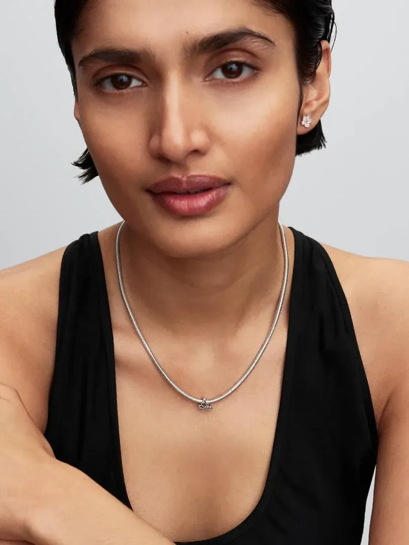 Primer plano de collar con charm de mariposa sobre modelo, toma frontal, fondo neutro.