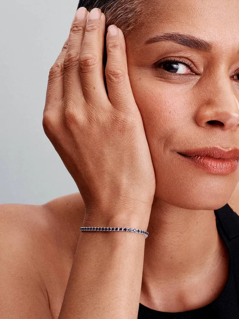 Primer plano de la pulsera azul en la muñeca, toma lateral con modelo sobre fondo neutro.