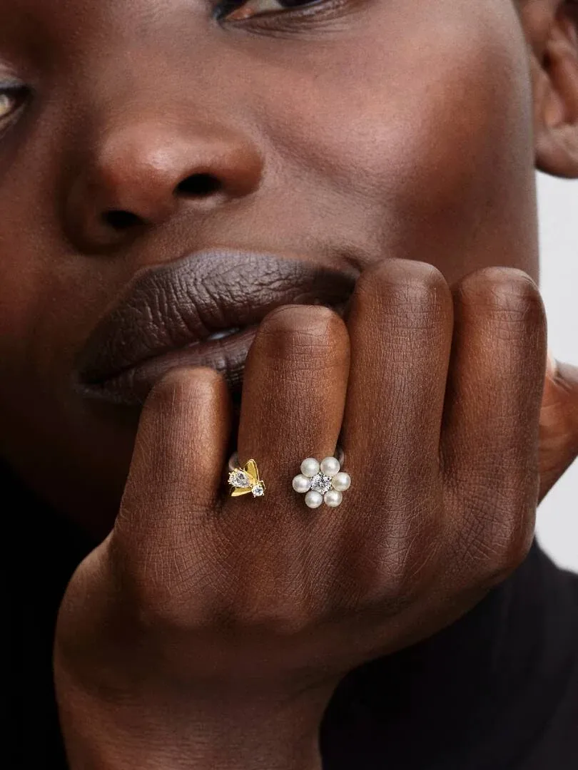 Primer plano del anillo abierto con abeja y perla puesto en el dedo, toma lateral sobre mano de modelo.