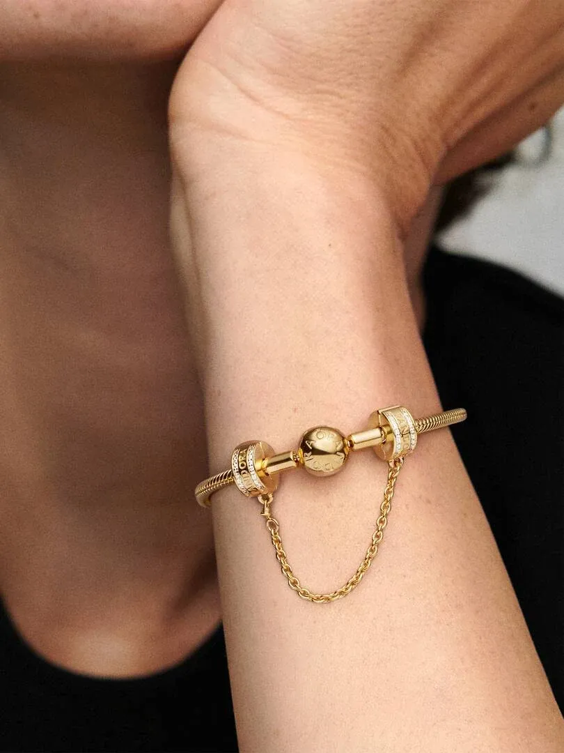 Gros plan du charm clip doré avec chaîne sur un poignet, vue de profil.