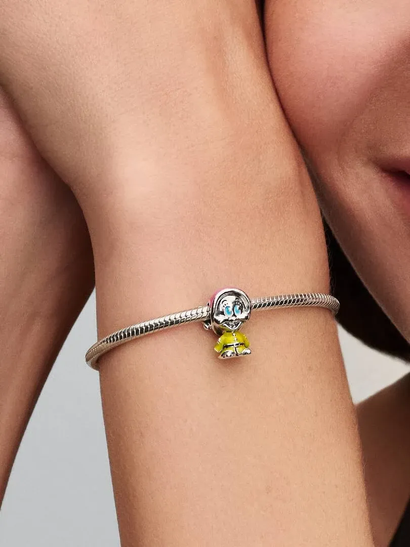 Primer plano del charm de Mudito en una pulsera de plata, sujeto a la muñeca de una modelo.