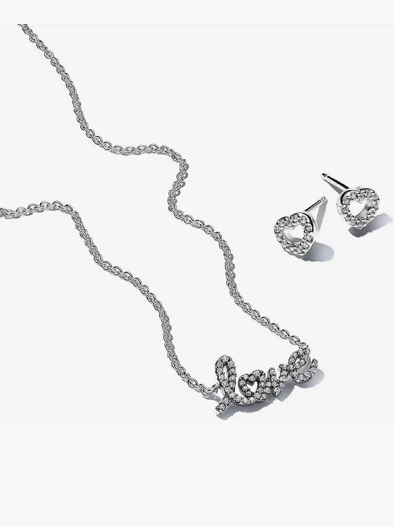 Collar con colgante 'love' y pendientes de corazón, vista superior sobre fondo blanco.