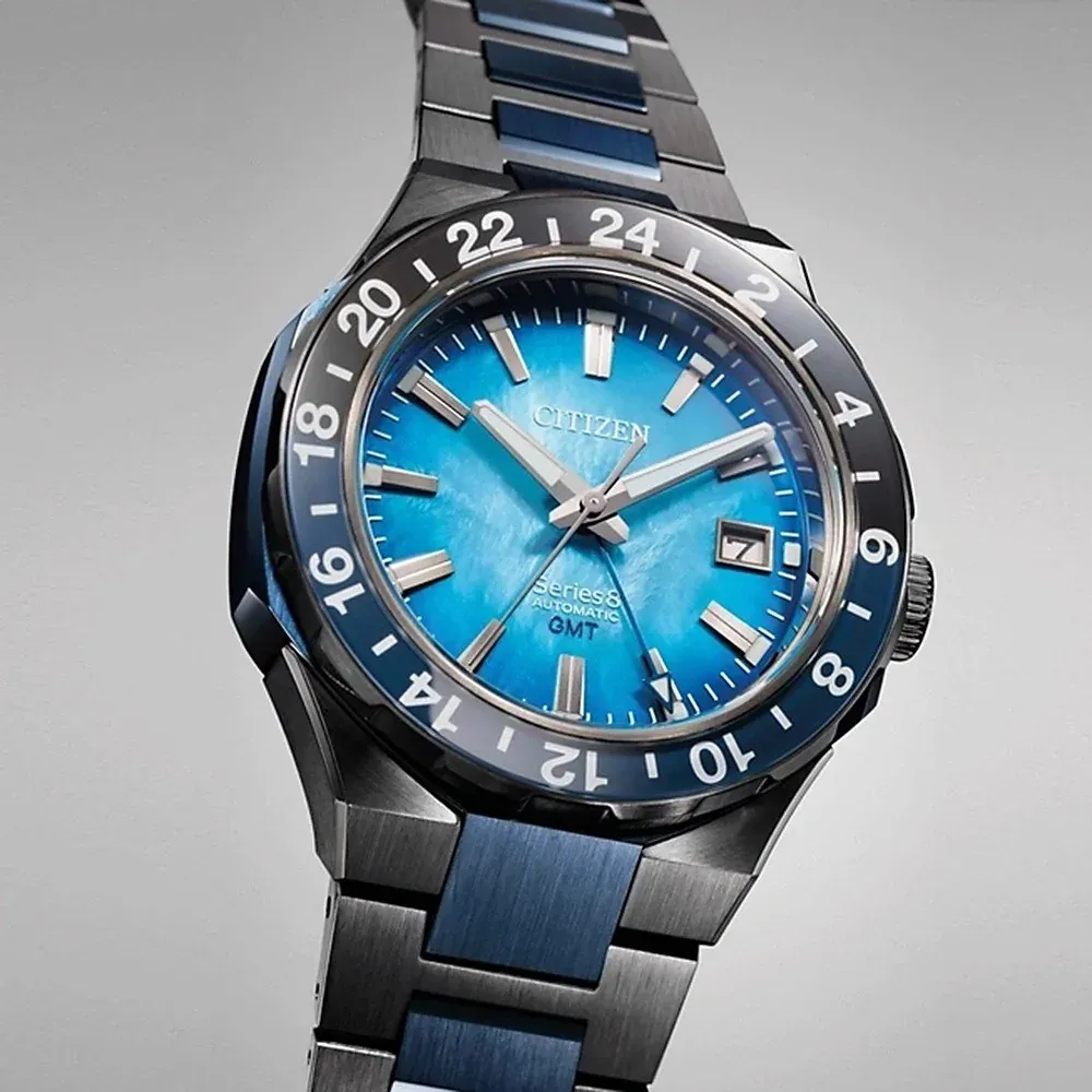 Primer plano en ángulo del dial azul texturizado y el bisel numerado sobre fondo gris neutro