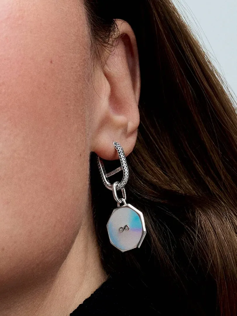 Gros plan latéral d'une boucle d'oreille créole pavée portée à l'oreille, fond flou.