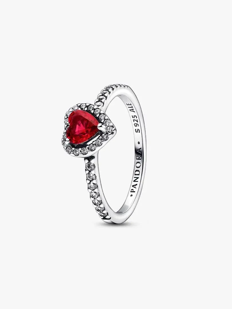 Anillo de plata con corazón rojo visto en ángulo lateral, fondo blanco, detalle del grabado interno.