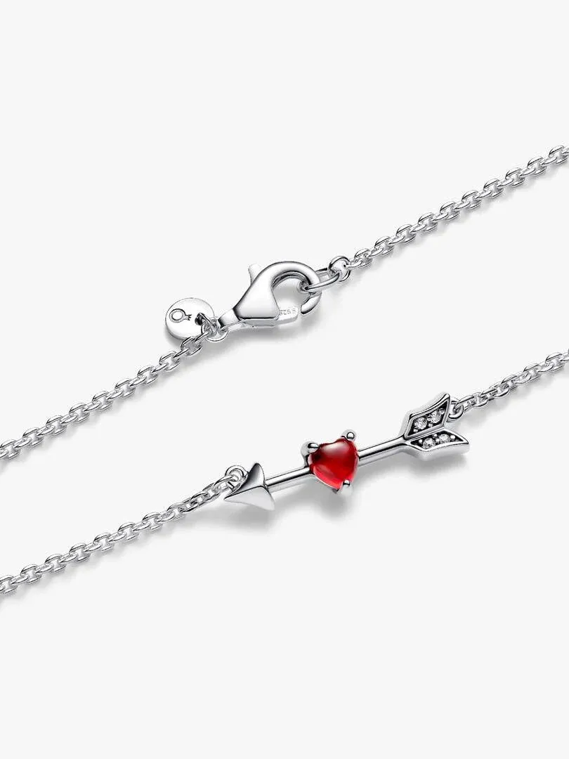 Silver necklace laid flat on a white background, showing the lobster clasp and arrow pendant with red heart.
