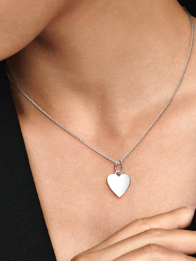 Primer plano de colgante de corazón de plata sobre el cuello y pecho, toma frontal con modelo.